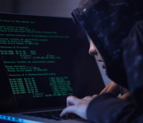 computer-hacker-in-hooded-shirt-typing-software-algorithms-and-stealing-data-from-computer-network-on-laptop